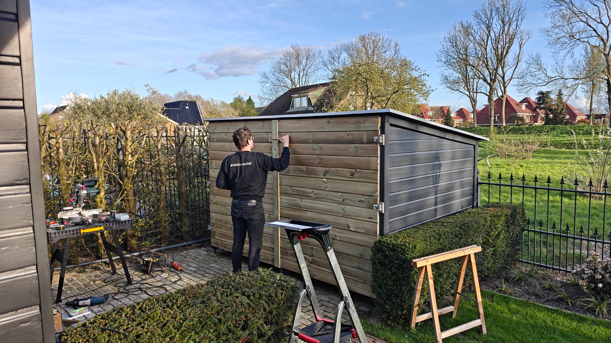 Gijs Oostveen aan het werk aan een houten berging.